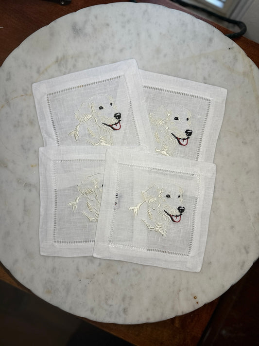 Four English Cream Retriever embroidered cocktail napkins arranged on a marble tray