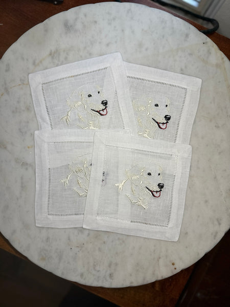 Four English Cream Retriever embroidered cocktail napkins arranged on a marble tray